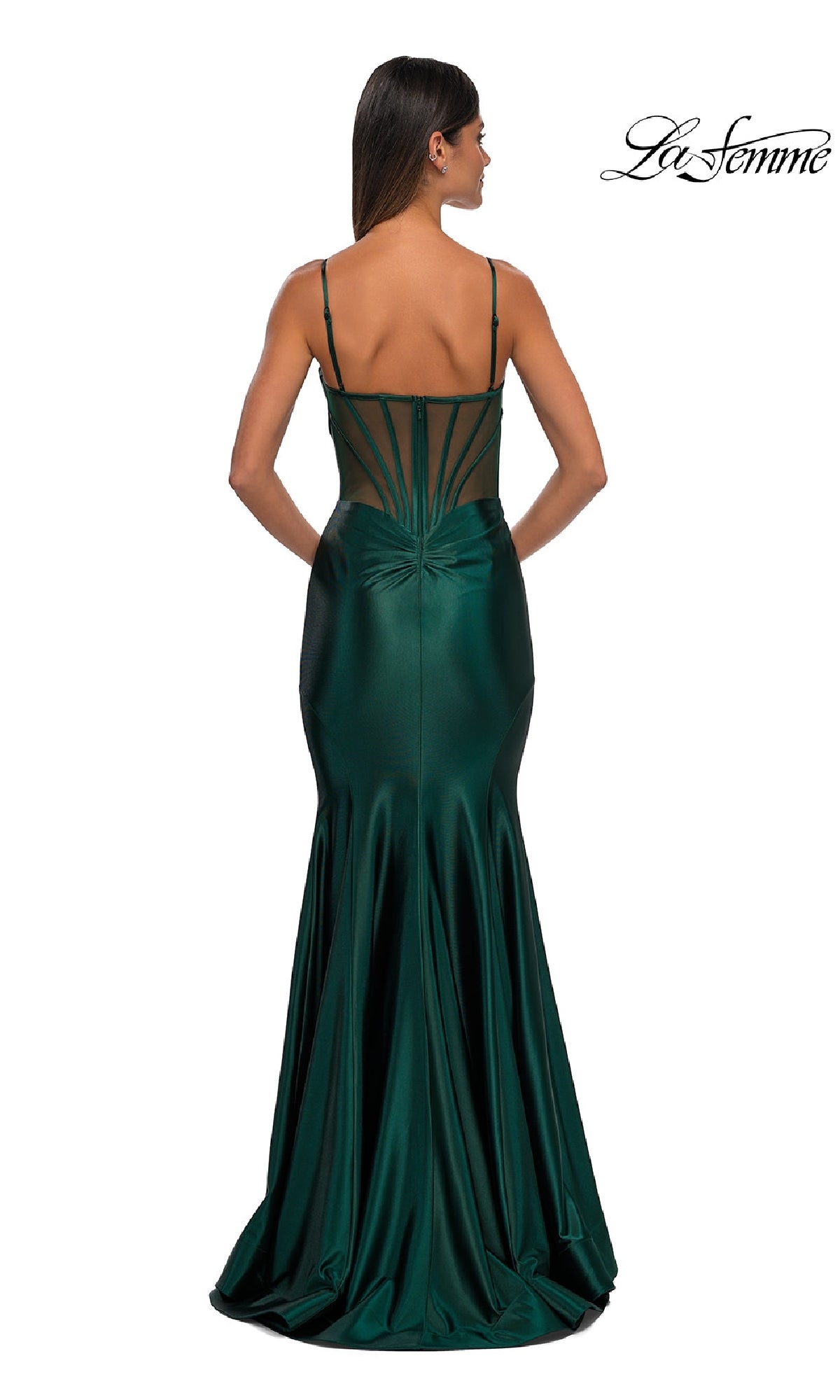 A woman faces away from the camera, wearing the La Femme 32555 long corset mermaid prom dress in dark green satin with spaghetti straps, a fitted sheer back, and a flared skirt.